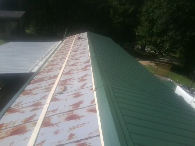 Old rusted panels beside newly installed green metal roofing — Wind Damage Roof Repair by Roofing Brothers in Tarentum