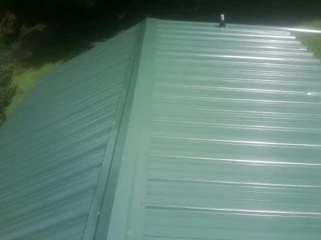 New green metal panels meeting at the ridge of a roof — Flat Roof Repair work by our crew in Tarentum