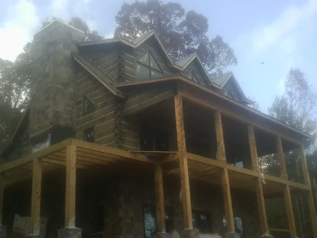 Stone chimney and dormers on a large log home with a timber porch in Tarentum