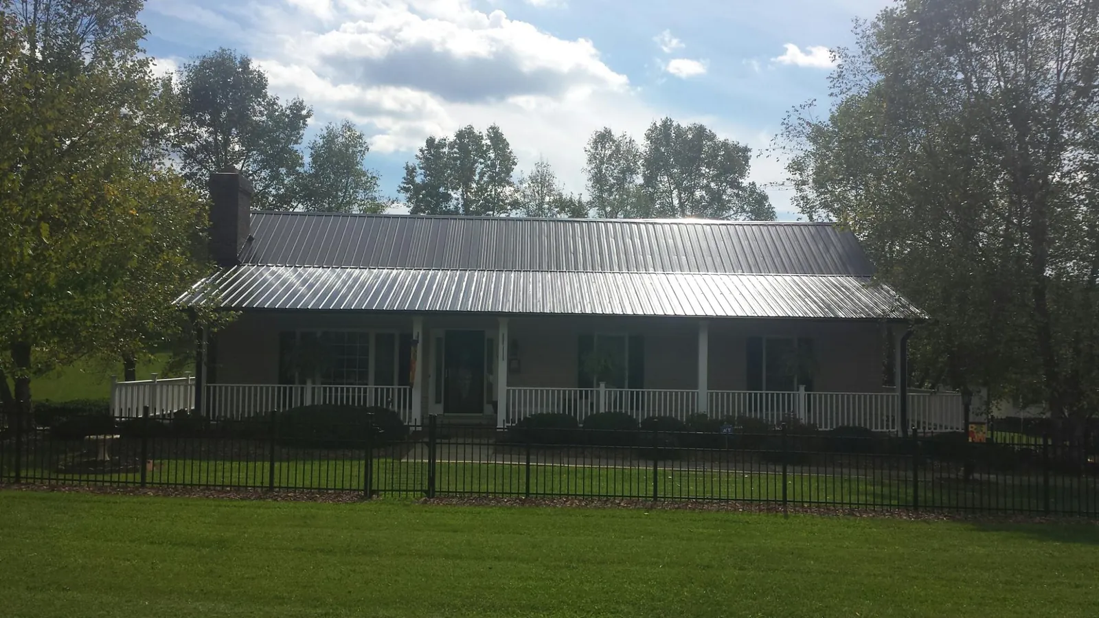 Gray metal roof on a brick ranch with a full width front porch — Gutter Guard Installation work by our crew in Tarentum
