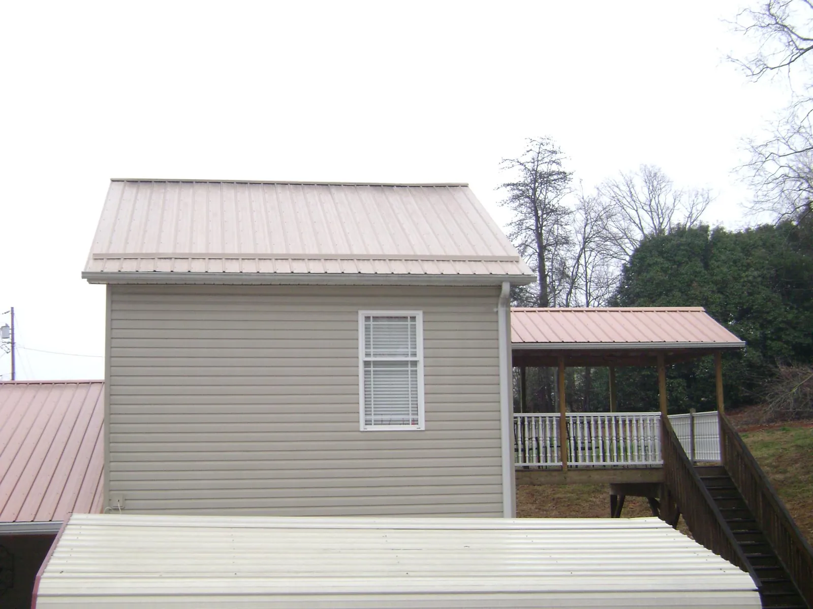 Tan metal roofs on a two story addition and attached porch, from a Roof Replacement job in Tarentum
