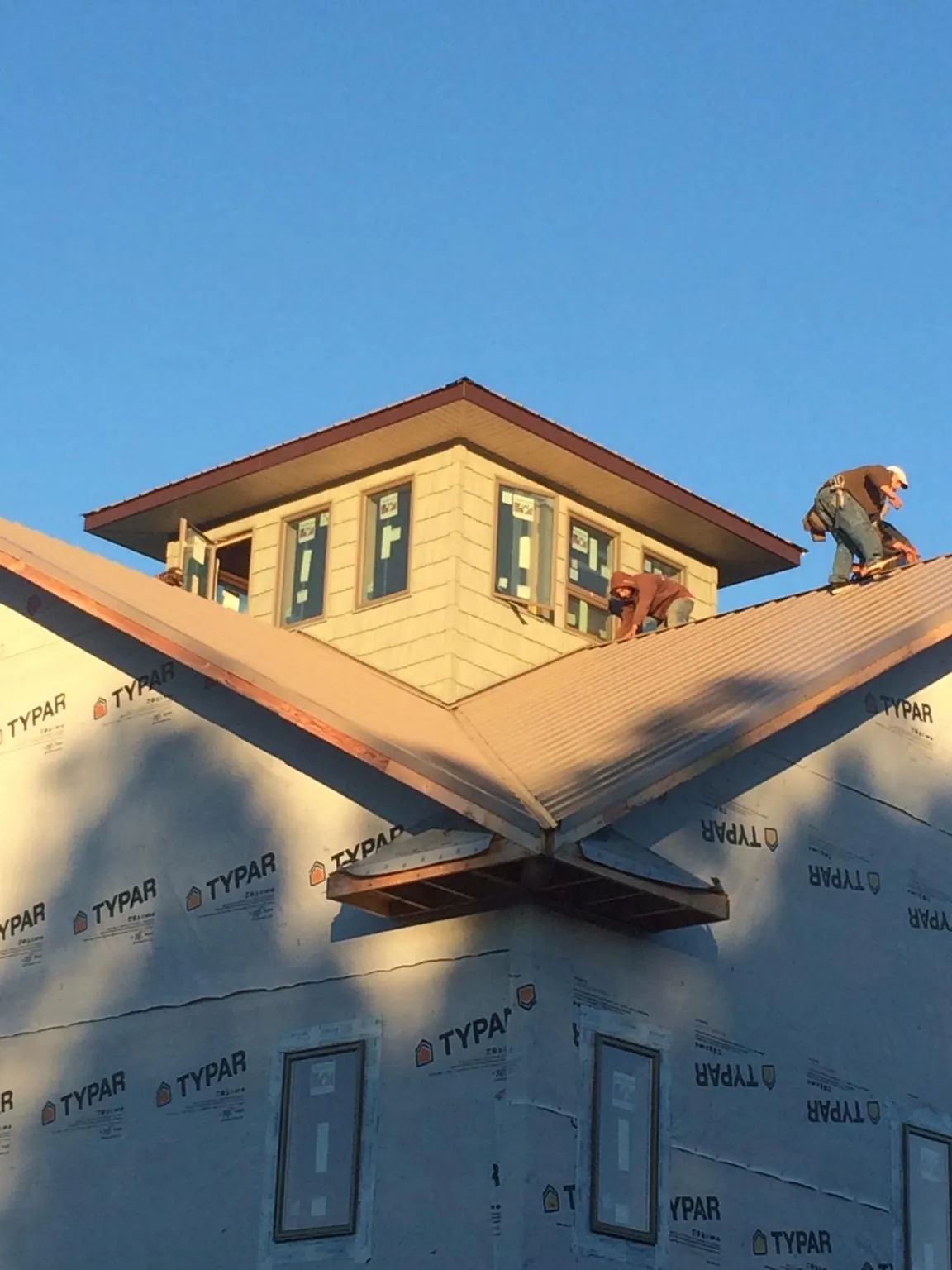 Roofers working around a rooftop cupola on a new metal roof at sunset — Roof Waterproofing in Tarentum by Roofing Brothers